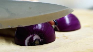 Kadın kırmızı, mor soğan bir ahşap tahta bıçak yakın çekim ile keser