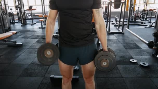 Hombre atlético bombeando los músculos, haciendo ejercicios de culturismo en el gimnasio — Vídeo de stock