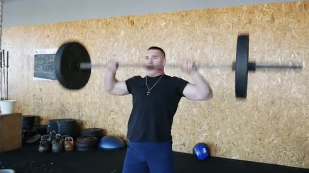 Hombre atlético trabajando duro en el gimnasio, trenes con barra, entrenamiento crossfit — Vídeo de stock