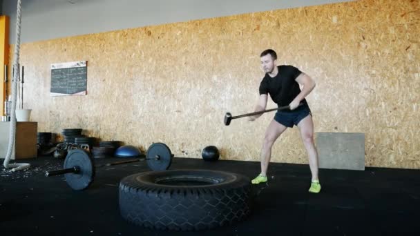 Hombre musculoso golpeando neumático con un martillo, concepto de fitness en cámara lenta — Vídeo de stock