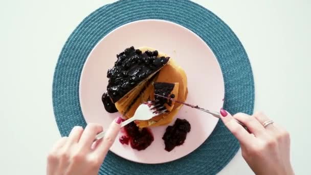 Woman eating berries pancakes with knife and fork, top view, morning breakfast — Stock Video