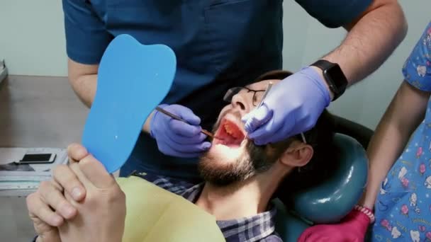 Patient en clinique dentaire. Le dentiste prépare la dent de l'homme pour remplir une dent — Video