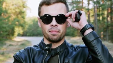 Kameraya bakan, gözlüklerini çıkarıp gülümseyen başarılı bir adamın yakın çekim portresi