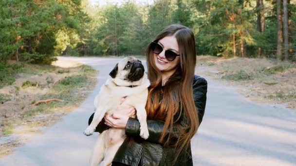 Hermosa mujer abrazo caricia divertido perro pug en el parque en cámara lenta — Vídeos de Stock