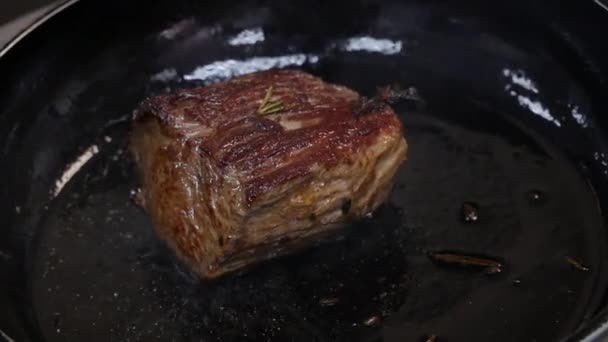 Velký steak se smažuje v pánvi v kuchyni v restauraci v těsné blízkosti — Stock video