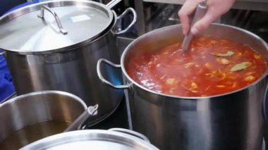 Bir restoranda bir aşçı büyük bir tavada borsch karıştırır