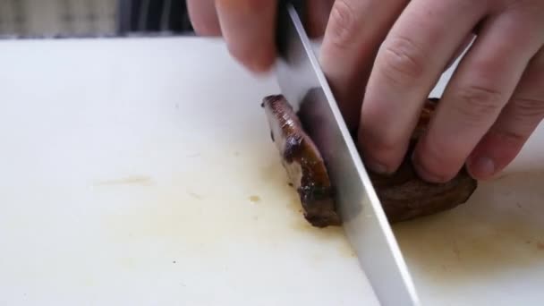 Közeli a szakácsok keze, amely csökkenti a hús, közepes ritka steak — Stock videók