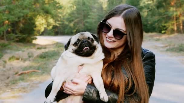 Retrato de chica elegante abrazo caricia perro divertido pug en el parque en cámara lenta — Vídeos de Stock