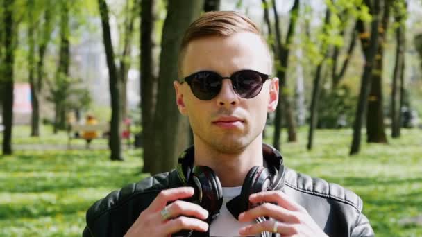 Close-up retrato de estudante atraente, homem coloca fones de ouvido ouvindo música — Vídeo de Stock