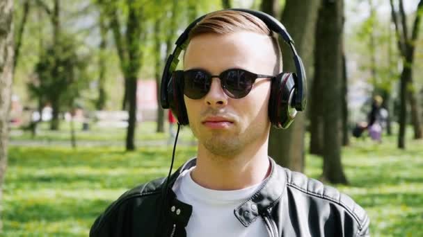 Κοντινό-up πορτραίτο του ελκυστικού καυκάσιου ανθρώπου, ακούγοντας μουσική στα ακουστικά — Αρχείο Βίντεο