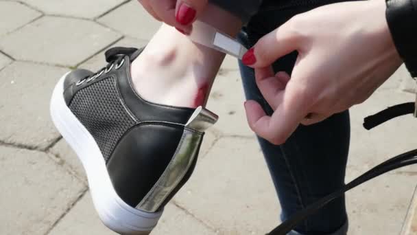 Lány puccs egy vakolat a sebet, dörzsölte lábát a cipők — Stock videók
