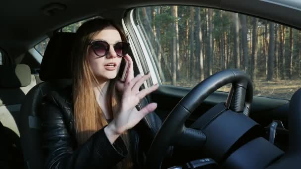 자동차의 바퀴에 앉아, 휴대 전화에 이야기 세련된 여자 — 비디오