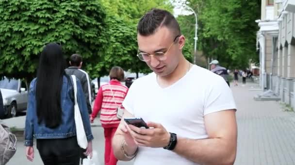 Молодой успешный человек пользуется мобильным телефоном на улице — стоковое видео