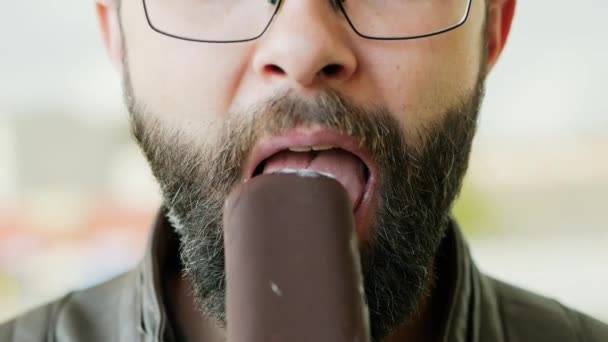 Крупный план портрета голодного бородатого человека, поедающего мороженое — стоковое видео