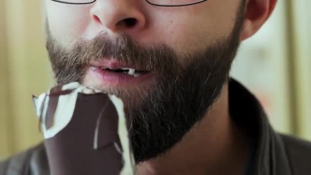 Крупним планом портрет голодного бородатого чоловіка, який їсть шоколадне морозиво повністю — стокове відео