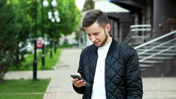 Hombre alegre moderno utiliza el teléfono en la calle — Vídeo de stock