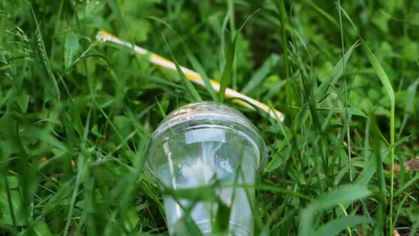 Womens hands remove the plastic cup from the grass, removing plastic — ストック動画