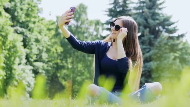 Hermosa mujer tomando selfie en el teléfono inteligente. Pasar tiempo en el parque de la ciudad — Vídeos de Stock