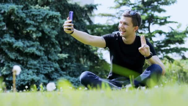 Счастливчик делает селфи на смартфоне. Проведение времени в городском парке — стоковое видео