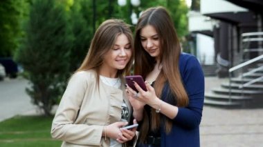 Mutlu kız arkadaşlar telefonla online alışveriş yapmak, kızlar mal seçin, kadınlar alışveriş yapmak