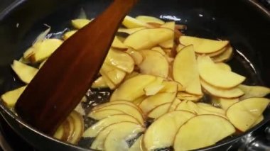 Cook bir tavada bir spatula ile çiğ patates karıştırır