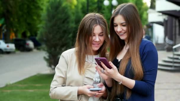 Ragazze candide utilizzano smartphone alla ricerca di una foto, gioco, applicazione, shopping online — Video Stock