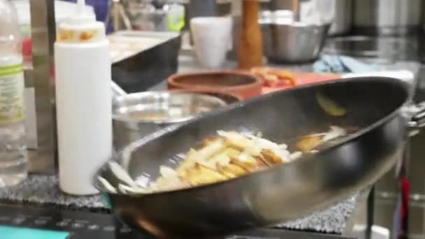 요리사가 레스토랑의 주방에서 적극적으로 일하면서 프라이팬에 튀긴 감자를 던지다 — 비디오