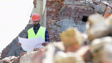 Ciddi oluşturucu çizim analiz. Yıkılmış bina arka plan üzerinde kask sakallı bina mühendisi.