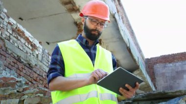 Bir kask kullanmak tablet bir mühendis Oluşturucu, bina yıkım planı ve inşaat projesine bakıyor