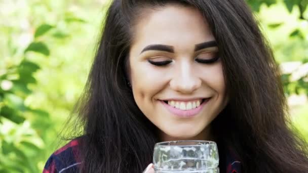 Portret młodej szczęśliwej pięknej kobiety, która pije piwo ze szkła, gasić pragnienie, uśmiech i patrząc na kamerę — Wideo stockowe
