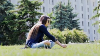 Kız çayır bir şehir parkında oturan karahindiba üfleme, şehirde dinlenme