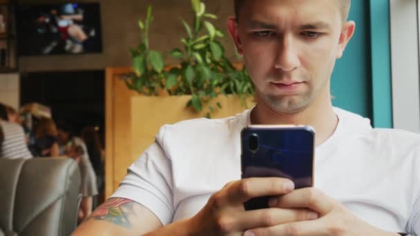 Gros plan portrait de jeune homme utilise téléphone portable dans un café — Video