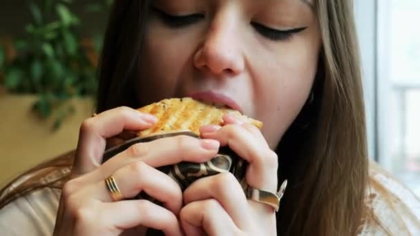 Primer plano de la joven hambrienta come tostadas en un café, restaurante de comida rápida — Vídeos de Stock