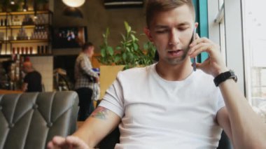 Meşgul genç adam bir kafede bir cep telefonu konuşuyor