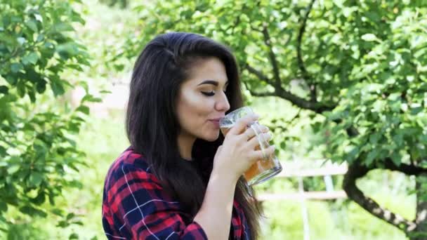 Side portrait of young happy woman drinks beer from glass, quenches thirst — Stock Video