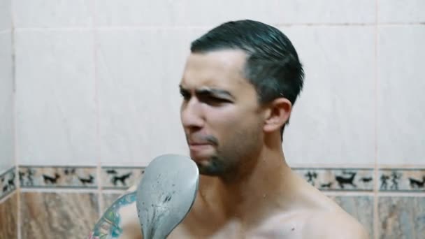 Portret śmiesznego mężczyzny śpiewającego z prysznicem jako mikrofon, mycie w łazience — Wideo stockowe