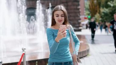 Cep telefonu kullanarak ve sokakta görüntülü arama ile arkadaşlarıile konuşurken Güzel mutlu kadın
