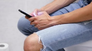 Yakın çekim erkek eller tuvalet tutarak telefon. Adam tuvalet akıllı telefon kullanımı