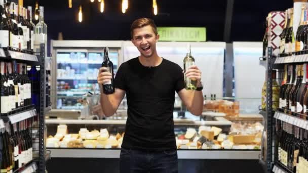 Ukraine, kiev 20.06.19: Ein fröhlicher junger Mann tanzt mit Weinflaschen in der Alkoholabteilung im Supermarkt zwischen den Reihen. das Wort Delikatessen auf einem Teller im Hintergrund. — Stockvideo