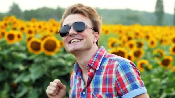 Porträt eines coolen männlichen Bauern, der auf Sonnenblumenfeld fröhlich und positiv im Sonnenuntergang tanzt. Bewirtschaftungskonzept — Stockvideo