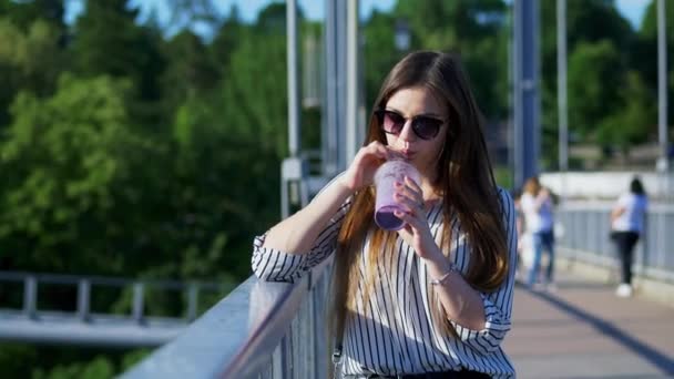 Όμορφη γυναίκα τουρίστες πίνει ένα κρύο κοκτέιλ στη γέφυρα — Αρχείο Βίντεο