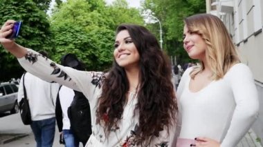 İki mutlu kız arkadaş sokakta telefonda selfie yapmak