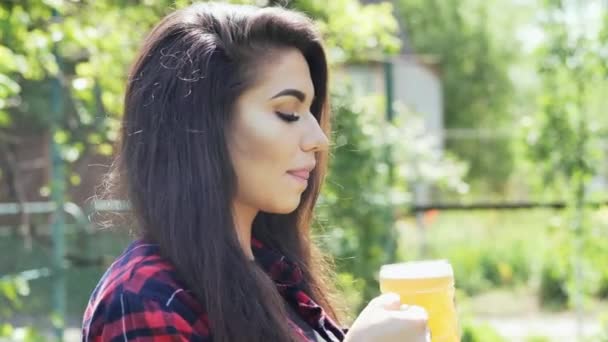 Genç mutlu kadın portresi bir barbekü de bahçede, camdan bira içecekler, susuzluk giderir — Stok video
