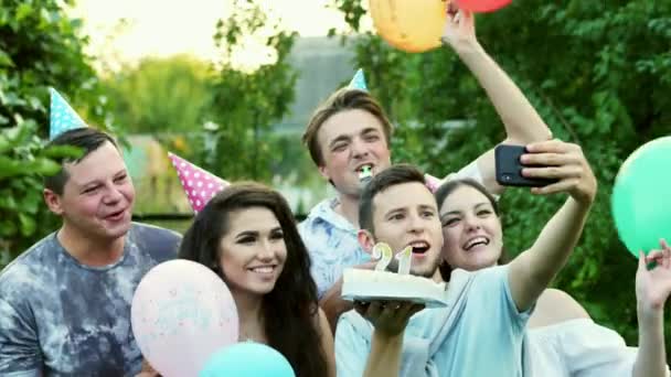 Homem feliz faz selfie no telefone celular enquanto celebra um aniversário, os amigos parabenizam, tiram uma foto no telefone celular — Vídeo de Stock