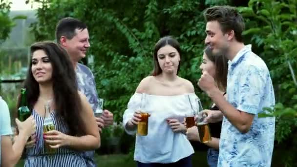 Група друзів клонують пляшки, п'ють пиво, люди танцюють в парку, вечірка . — стокове відео