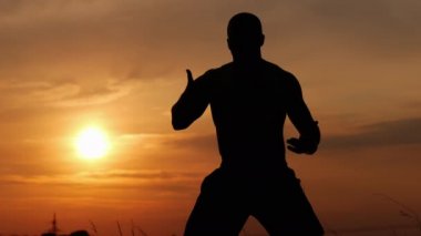 Bir savaşçı adam eğitim silueti, gün batımında bir nefes egzersiz ve meditasyon yapar