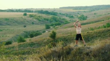 Güçlü adam tepelerde gün batımında tek başına nefes egzersizi yapar, akşam meditasyon