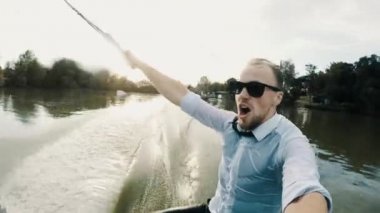Güneş gözlükle aşırı işadamının aksiyon kamerasında selfie gölün üzerinde wakeboard sürmek
