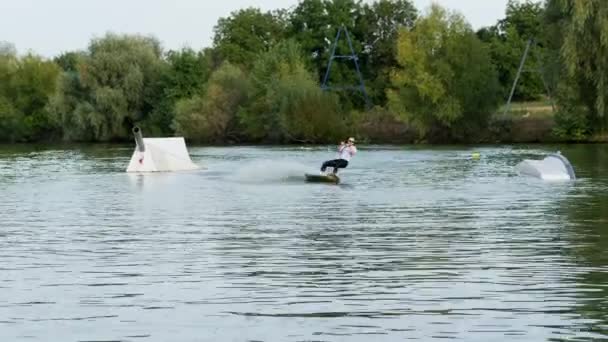 Bir göl üzerinde wakeboard üzerinde bir kravat ve güneş gözlüğü sürmek ile bir takım elbise aşırı ve komik işadamı — Stok video