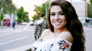 Başarılı kadın gün batımında akşam sokakta poz, arka planda insanlar ve arabalar